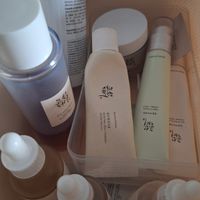 A collection of Korean skincare products with white and beige packaging arranged in a wooden tray or drawer