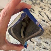 A person's hands holding an open book or magazine with pages fanned out, photographed against a granite countertop background