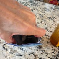 A hand holding a black smartphone over a speckled granite kitchen countertop