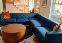Front view of the same blue sectional with round coffee table and rug, highlighting spacious seating in living room.
